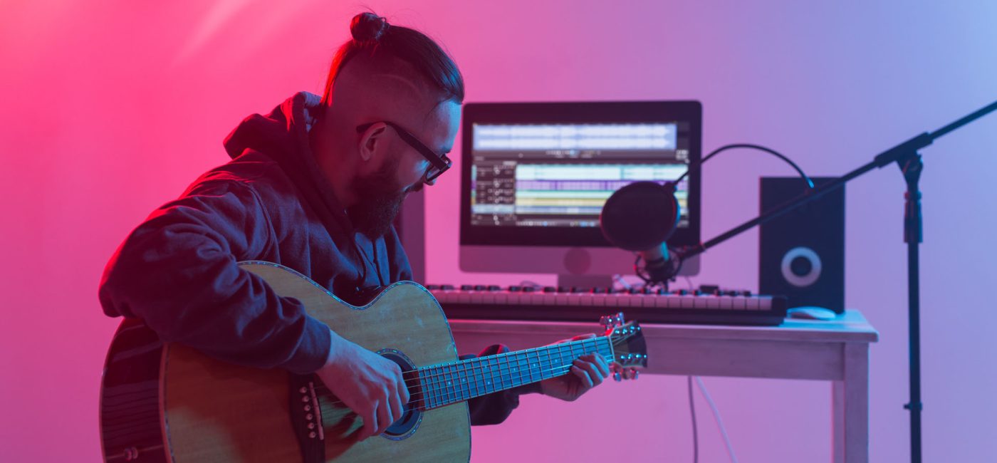 Create music and a recording studio concept - Bearded man guitarist recording electric guitar track in home studio.